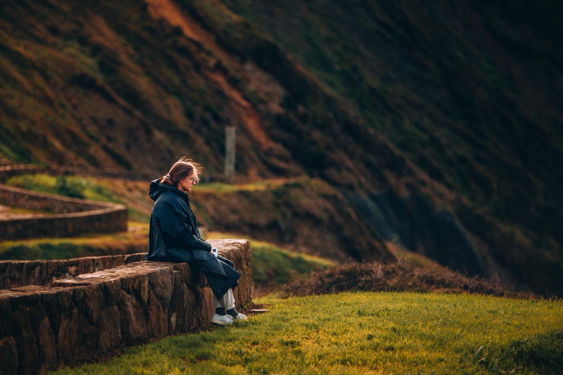 Women's mental health. Photo of a female hiker resting on a wall.