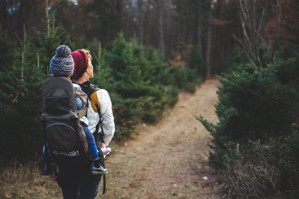 Women's mental health. Photo of woman with baby in baby carrier hiking through the woods.